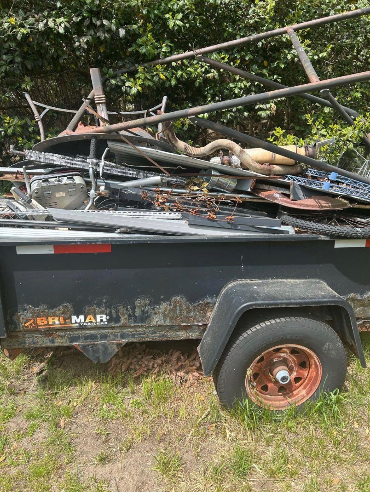 Amaru Bros trailer loaded with scrap metal, pipes, and wire shelving